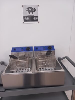 Front view of a Commercial Double Fryer with the lids removed and baskets hanging above the oil vats, highlighting the spacious, dual frying compartments for professional use.