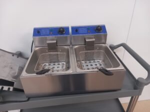 Front view of a Commercial Double Fryer with baskets inserted and lids removed, showing the dual fryers ready for use in busy commercial kitchens.