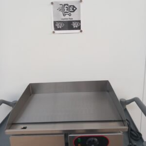 Front view of a 55cm commercial griddle with a flat stainless steel cooking plate, partially visible temperature controls, and an easy-access oil waste collection drawer for efficient commercial kitchen use.