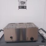 Front view of a commercial 3-pot bain marie with lids on, displaying the user-friendly control panel and water drainage tap for efficient food warming and easy water disposal in catering environments.