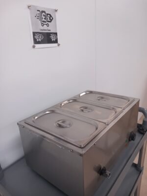 Angled left-side view of a commercial 3-pot bain marie, highlighting the stainless steel lids and built-in water drainage system for easy maintenance and cleaning in professional kitchens.