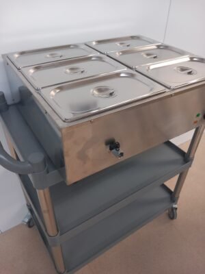 Lower left-angled view of a commercial 6-pot bain marie with lids on, showcasing the convenient water drainage system for easy cleaning and maintenance in busy catering environments.