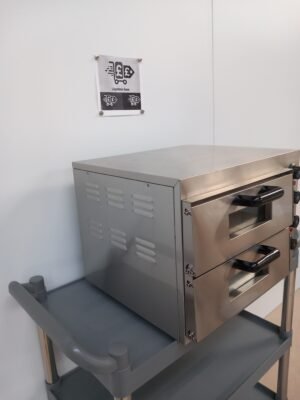 Left side view of a Twin Deck Commercial Pizza Oven with both doors shut, displaying its sturdy stainless steel body and space-efficient design for professional kitchens.