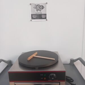 Front view of a commercial crepe maker featuring a 400mm Teflon-coated plate with a wooden crepe spreader placed on the surface, ideal for even and smooth crepe preparation in professional kitchens.