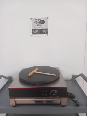 Front view of a commercial crepe maker featuring a 400mm Teflon-coated plate with a wooden crepe spreader placed on the surface, ideal for even and smooth crepe preparation in professional kitchens.