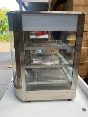 Right side view of a curved heated display showing three food racks through the transparent glass panel, providing a clear view of food items from multiple angles in a commercial environment.